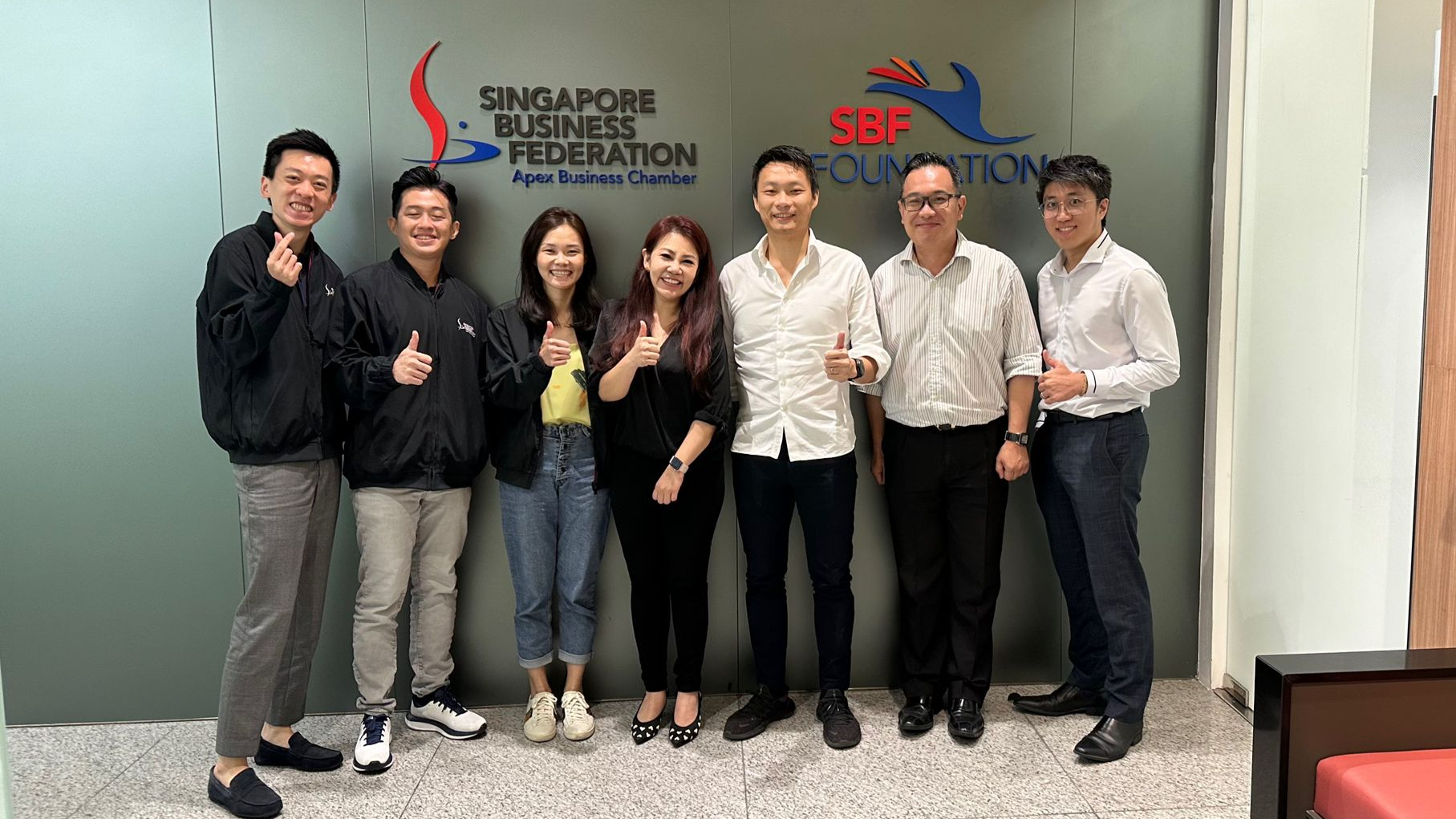 Group photo of Vision Group team member and Singapore Business Federation team in front of SBF logos.